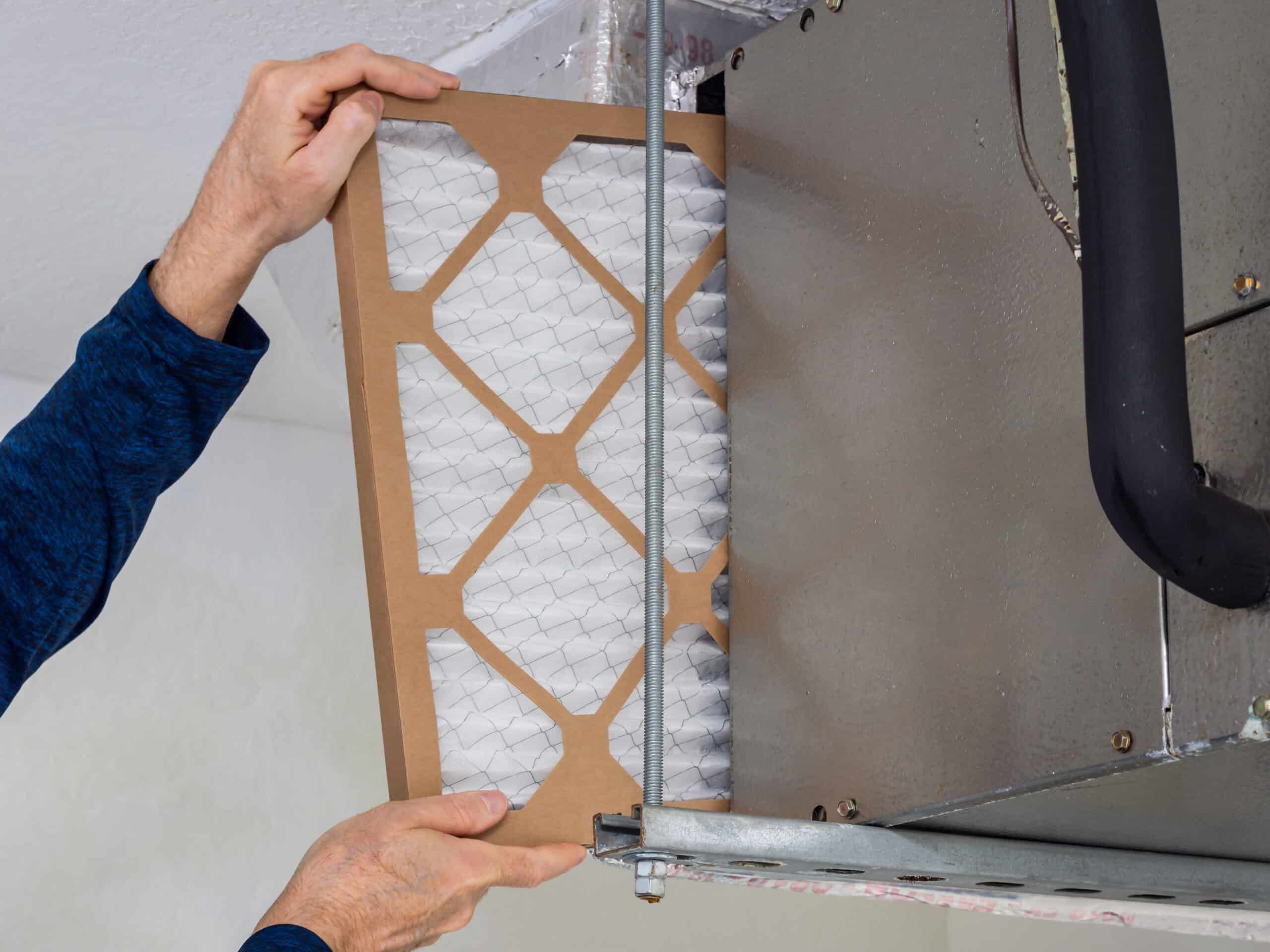 HVAC service technician changing dirty indoor air filter in residential heating and air conditioning system. Home air duct ventilation system maintenance for clean air. HVAC service technician changing dirty indoor air filter in residential heating and air conditioning system. Home air duct ventilation system maintenance for clean air.