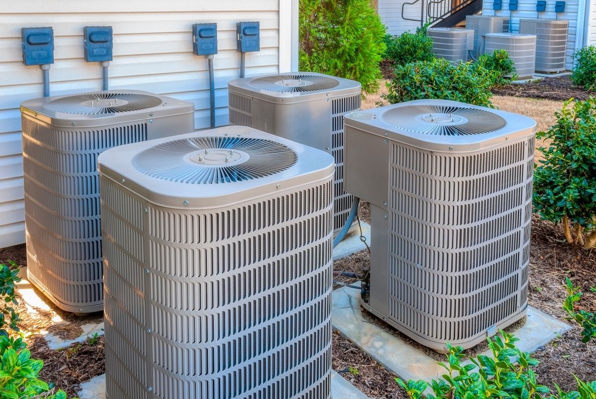 Horizontal shot of four air conditioning units outside of an upscale apartment complex. Horizontal shot of four air conditioning units outside of an upscale apartment complex.