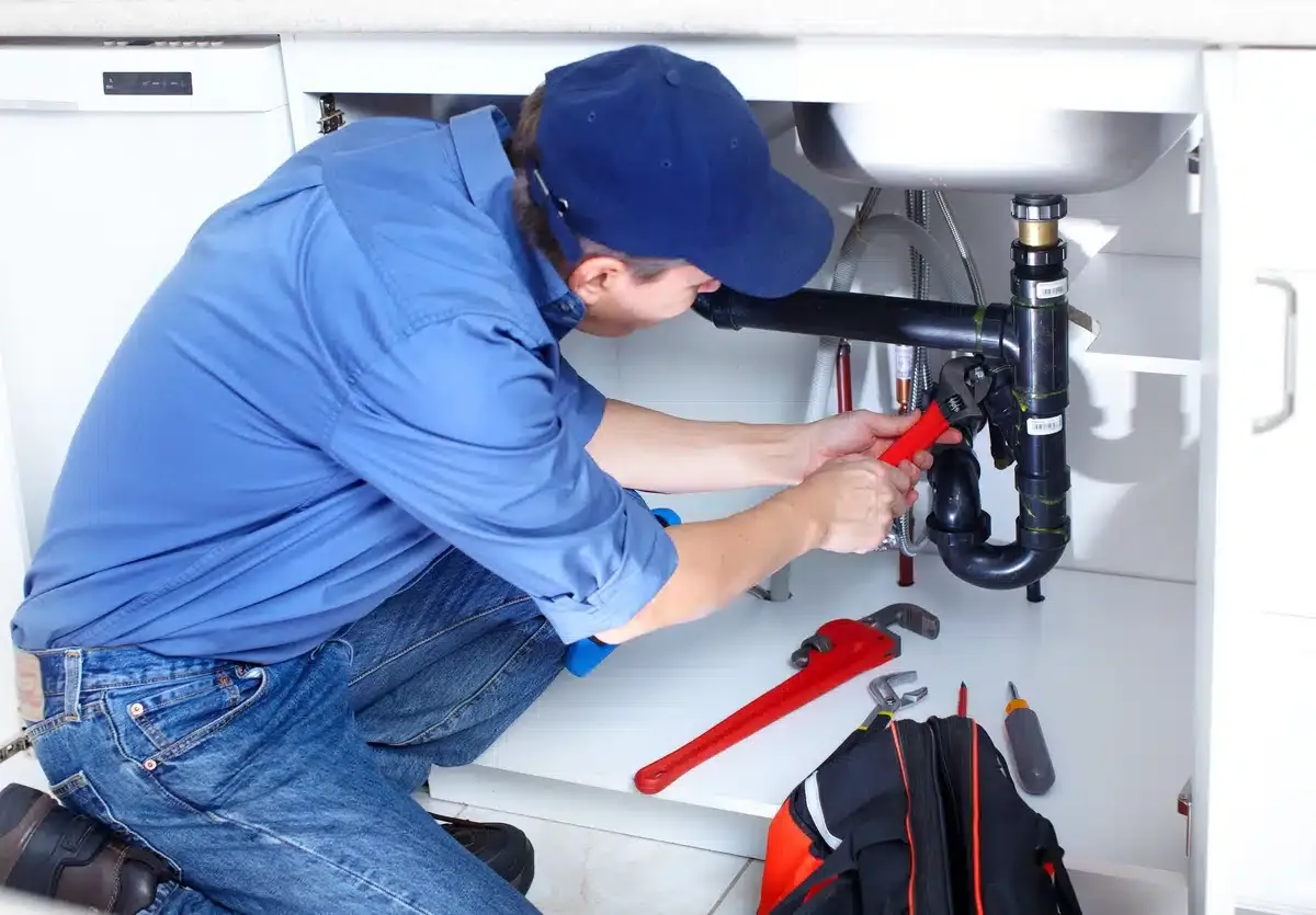 plumber using hand tools to fix a sink drain plumber using hand tools to fix a sink drain