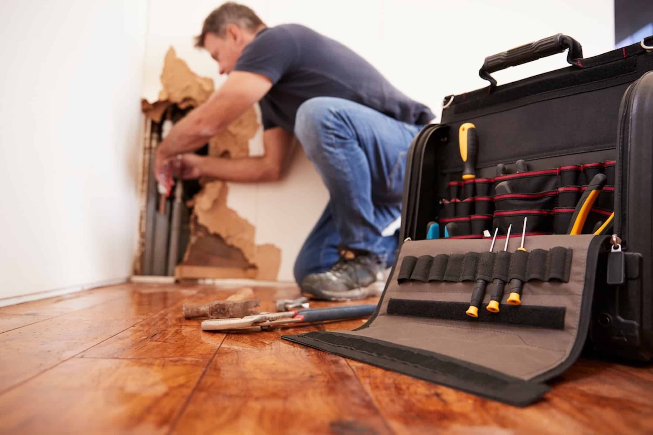 Middle aged man repairing burst pipe,plumbing, focus on foreground Middle aged man repairing burst pipe,plumbing, focus on foreground