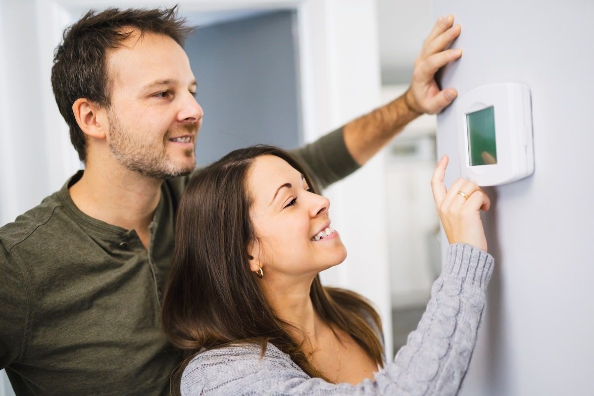 A couple set the thermostat at home A couple set the thermostat at home