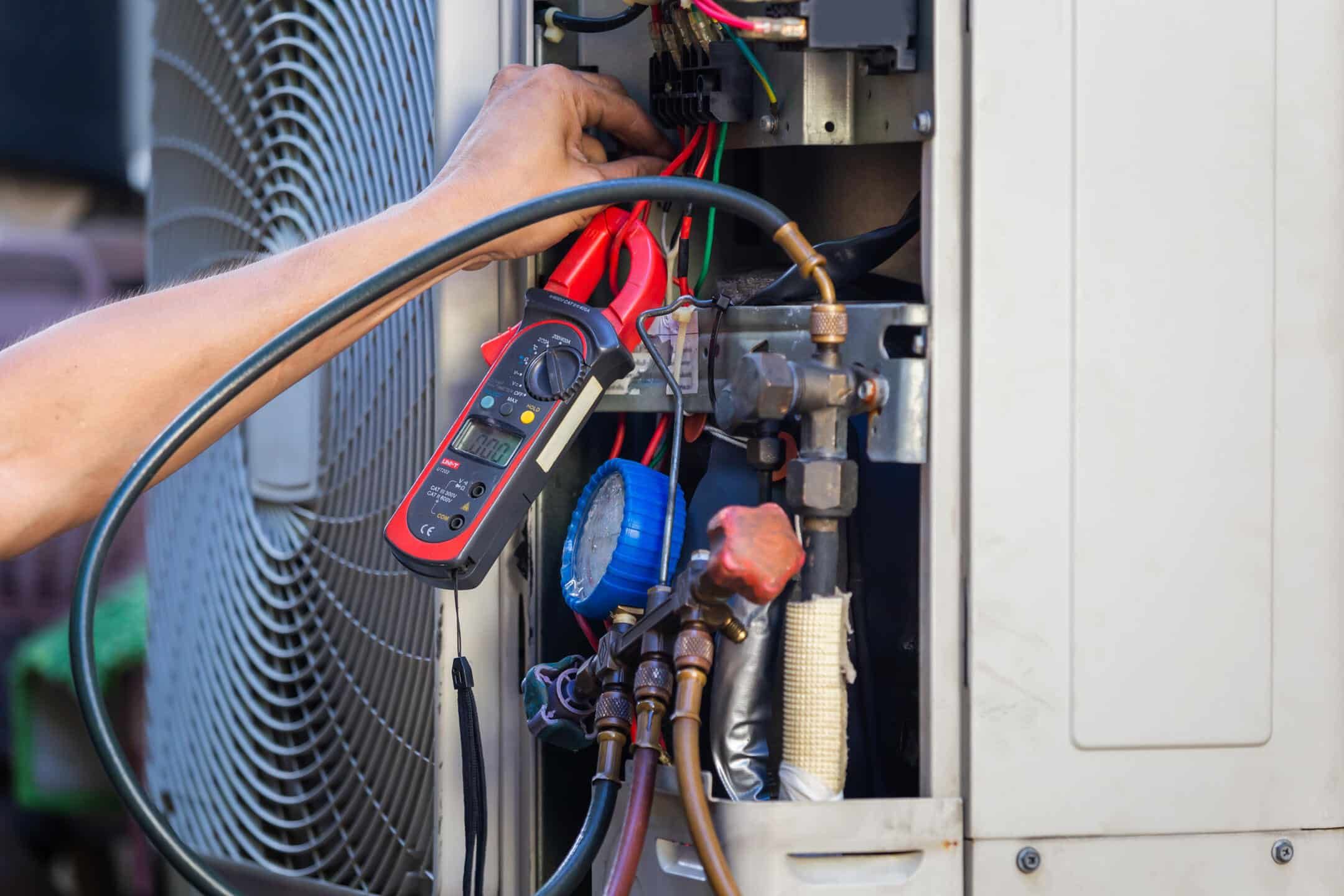 ac maintenance cost-close up of tech servicing central AC unit with tools ac maintenance cost-close up of tech servicing central AC unit with tools