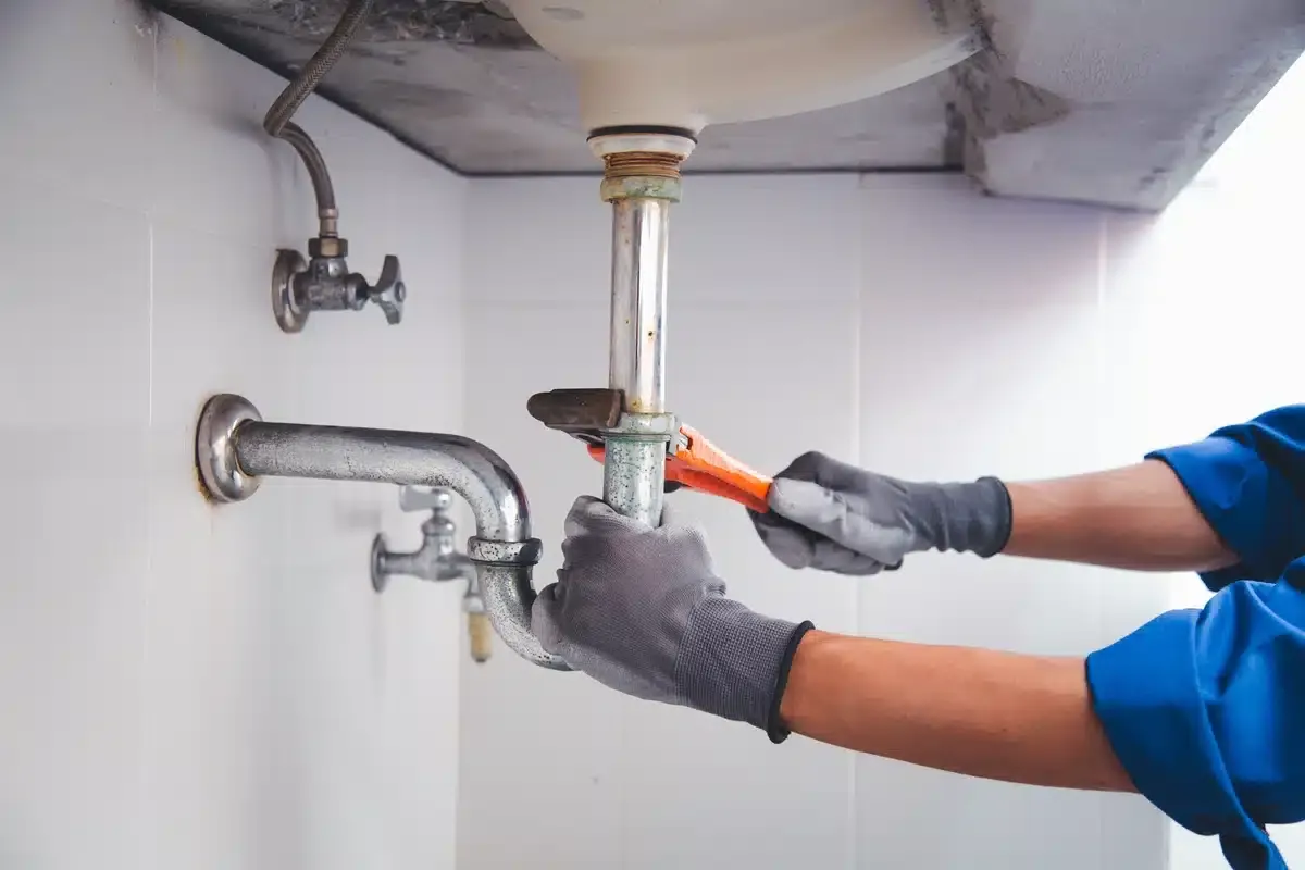 sink drain being serviced underneath the sink with a hand tool sink drain being serviced underneath the sink with a hand tool
