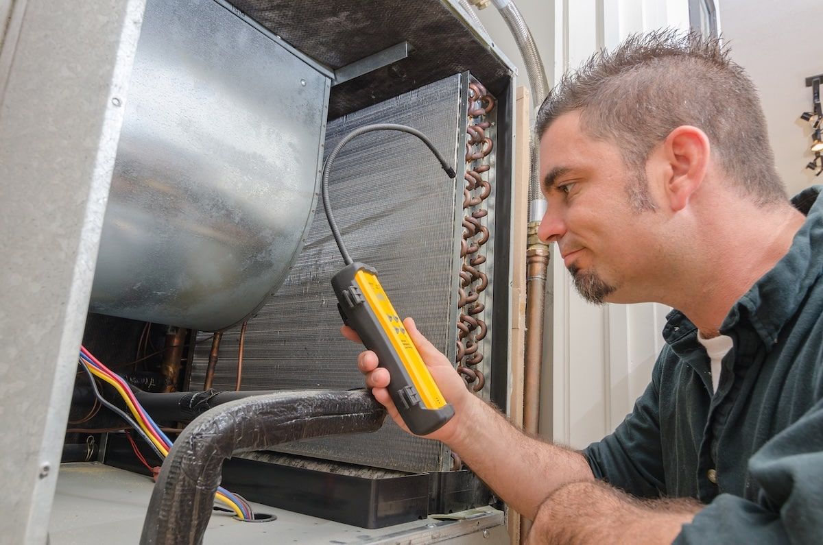 An Hvac technician searching for a refrigerant leak on an evaporator coil. An Hvac technician searching for a refrigerant leak on an evaporator coil.