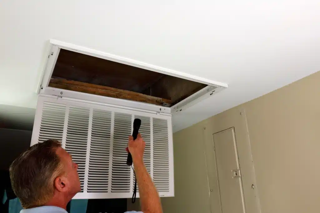 forced air heating-technician inspecting ductwork on forced air system