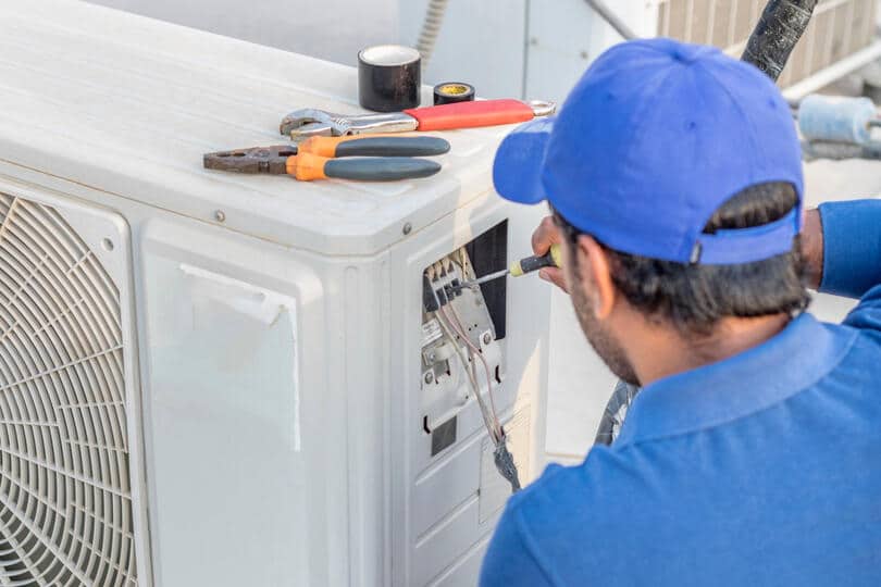 central air installation-repair tech using tools to install an ac unit