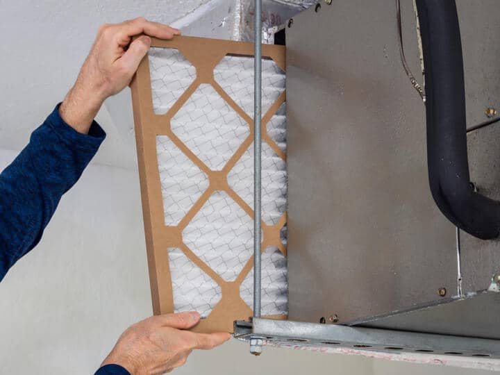 central air installation-technician inserting a new filter to central ac unit