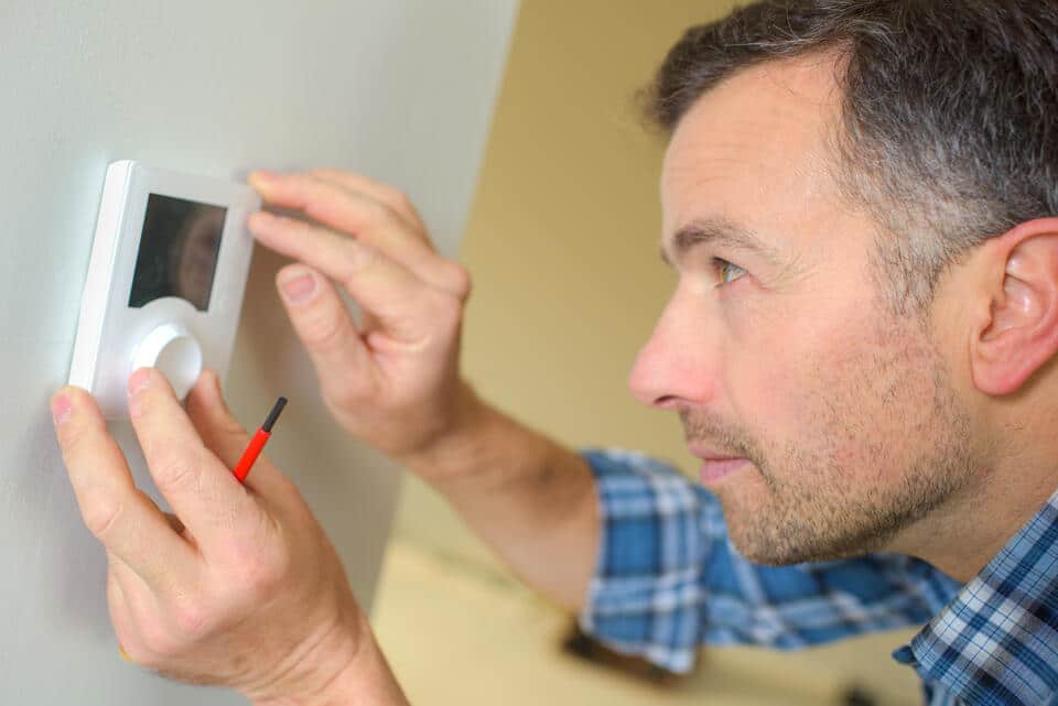 thermostat not working-man troubleshooting a thermostat