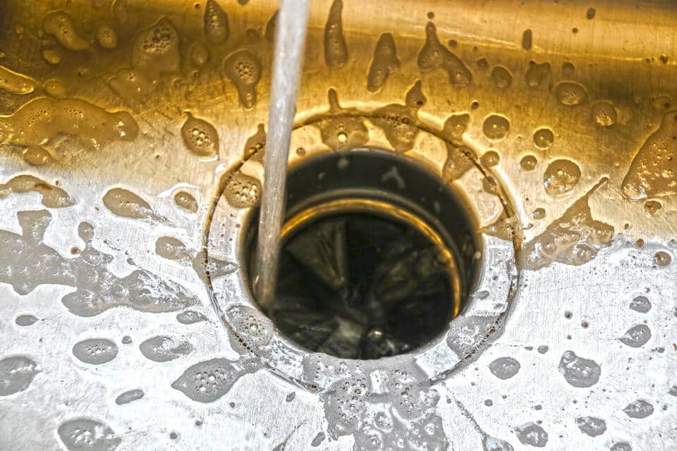how to unclog garbage disposal-close up of water and bubbles being rinsed down a garbage disposal