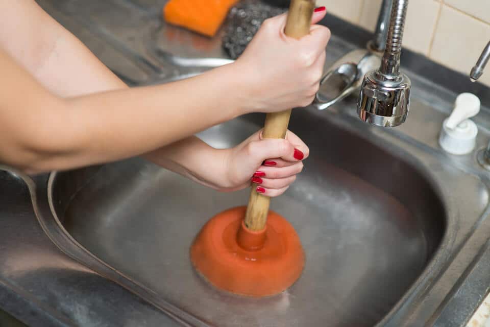 how to unclog sink-woman using a plunger to unclog a kitchen sink