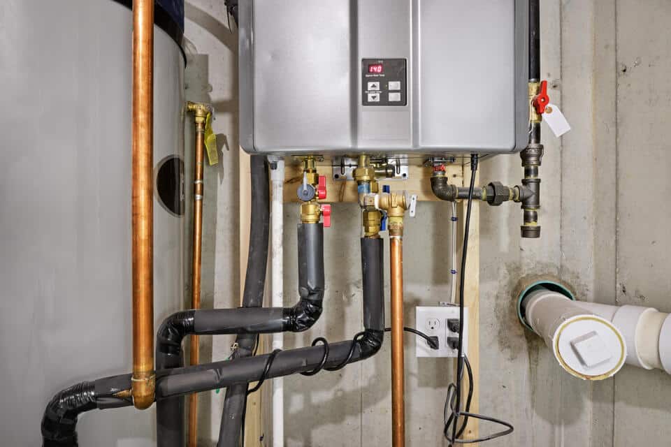 electric tankless water heater-close up of pipes and levers on a basement unit