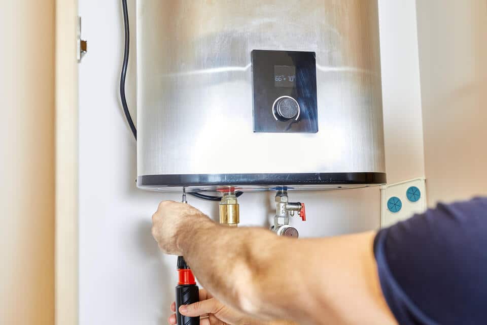 electric tankless water heater-man doing maintenance on a stainless steel unit