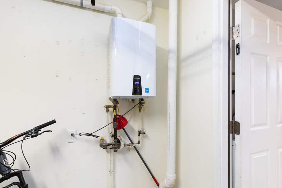 electric tankless water heater-white unit in basement or garage in a home