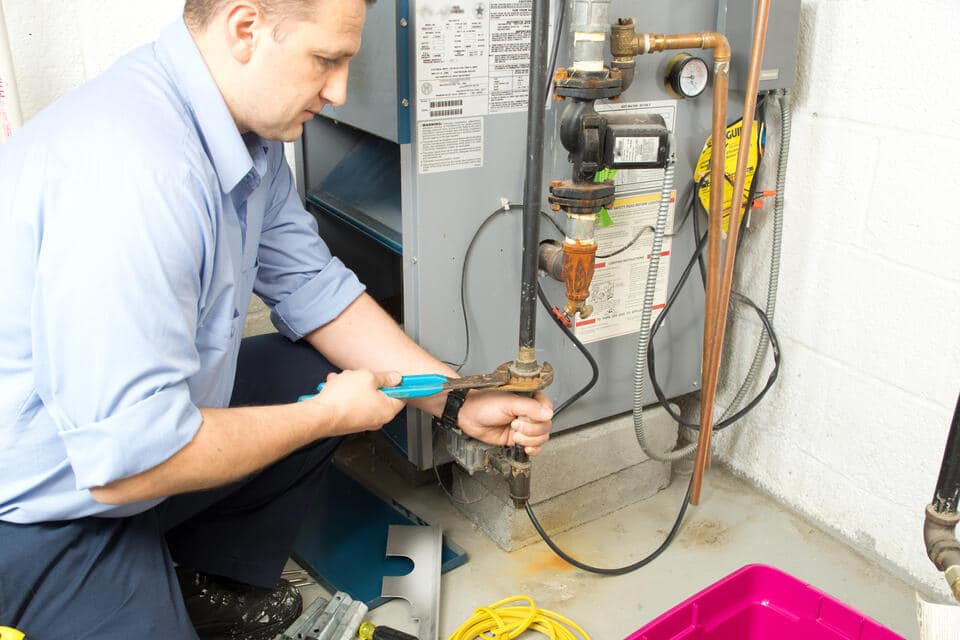gas furnace replacement cost-plumber performing maintenance on furnace