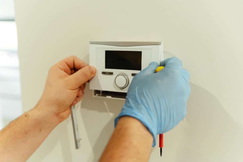 heating system repair-repair tech doing maintenance on a thermostat