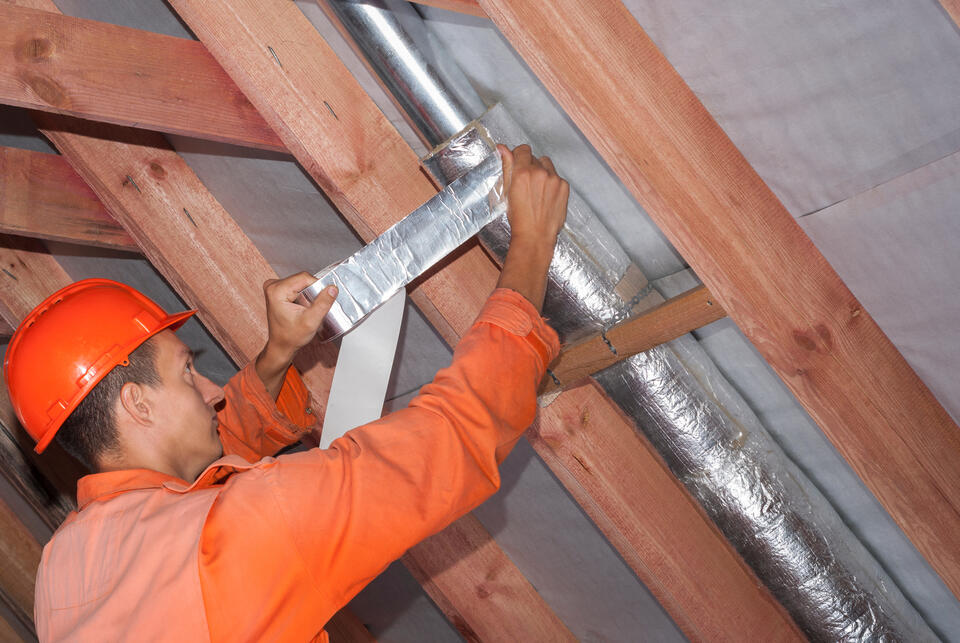 pipe insulation-tech wrapping large pipes in insulation materials between rafters