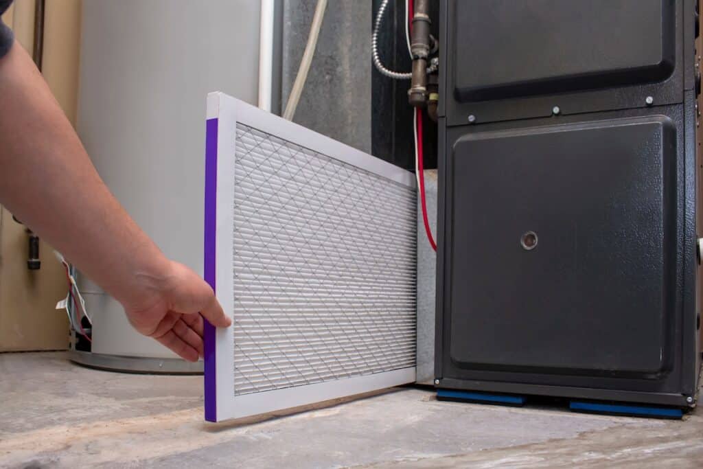 person changing air filter on furnace