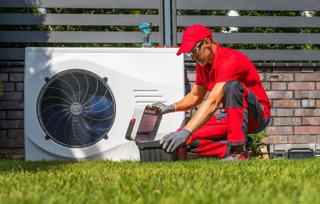 Professional Caucasian Heat Pumps Technician in His 40s Installing New Residential Modern Heating Device. HVAC Industry Theme. dc vs ac current