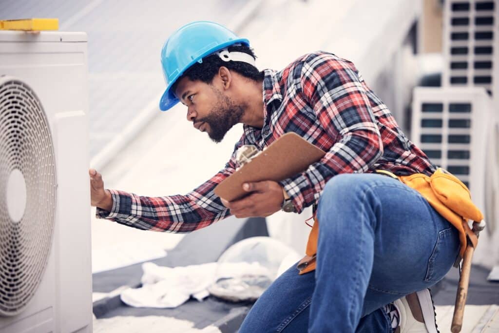 Technician, clipboard or air conditioning inspection on rooftop for safety, power or maintenance. Electrician, black man or paperwork on hvac system, ac repair or quality assurance for sustainability. hvac companies St. Michael