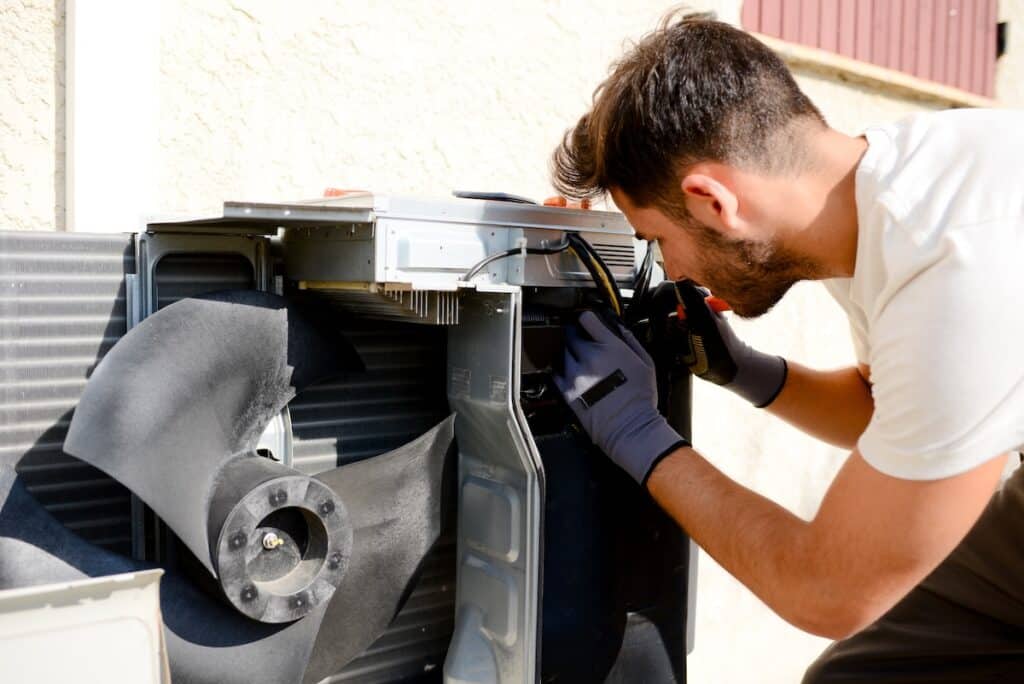 ac capacitor young man electrician installer working on outdoor compressor unit air conditioner at a client's home