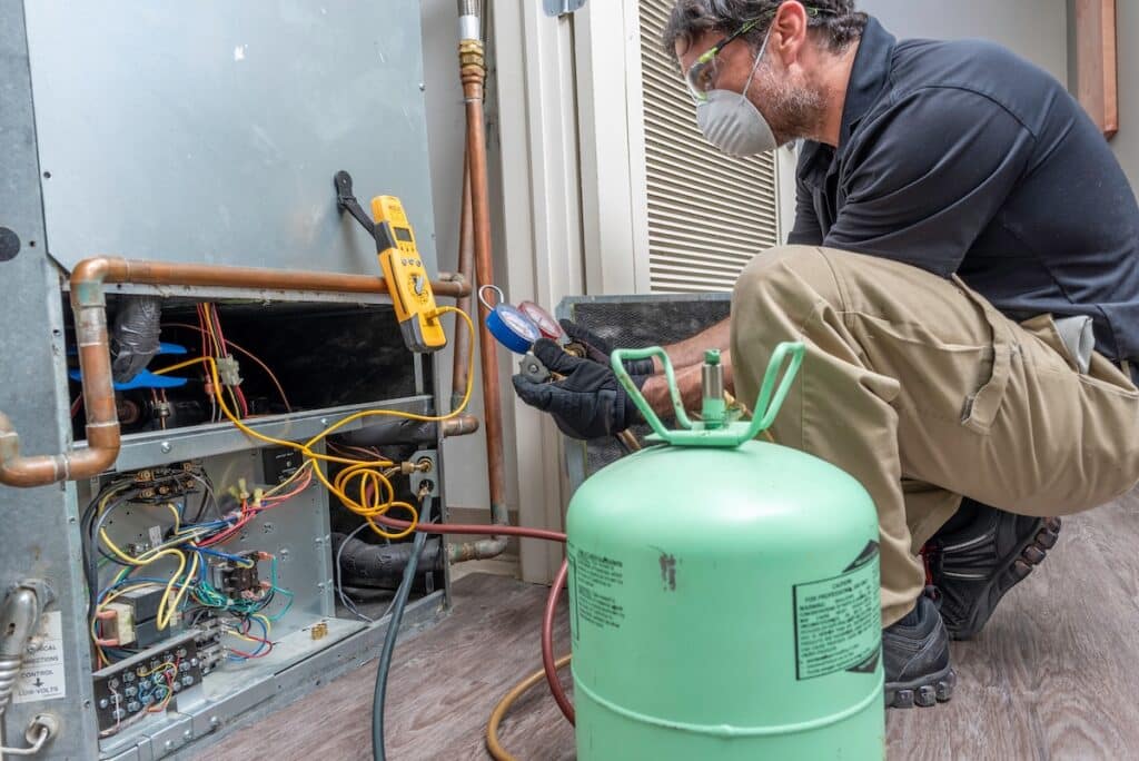 HVAC contractor wearing PPE, servicing a heat pump